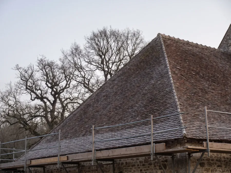 Toit en petites tuiles plates givrées d’une maison de village du Hurepoix, avec un échafaudage garde-corps le long de l’égout (illustration)